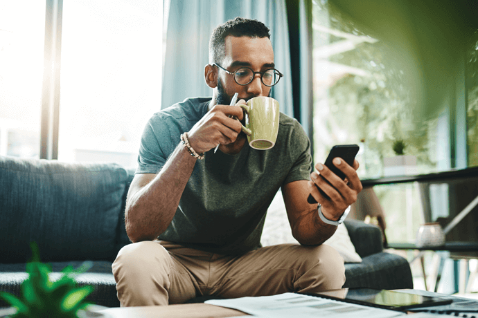 man drinking coffee and looking at phone