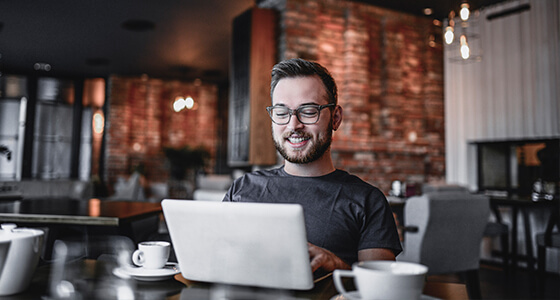 Man in a coffee shop reading laptop