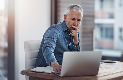 Man sitting at desk reading laptop